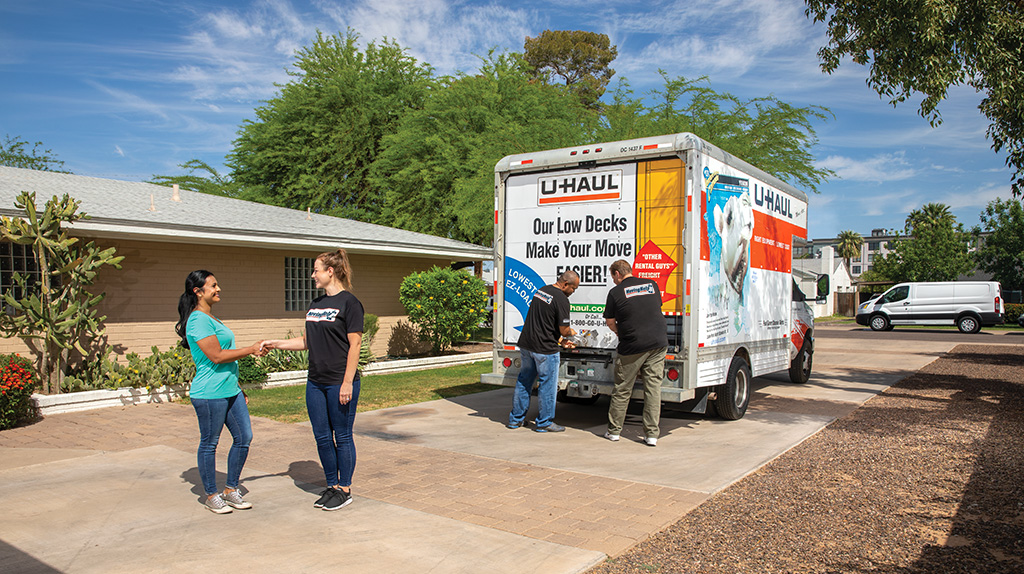 Customer shakes their mover's hand while the moving crew closes their U-Haul truck.