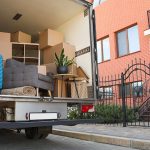 A loaded truck for a full-service move is parked outside of a townhome. By following some moving tips, you’ll know what to expect for the total cost of a full-service move.