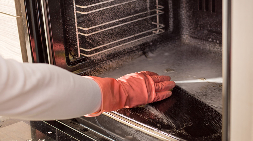 A woman cleans her oven using baking soda as an ingredient.