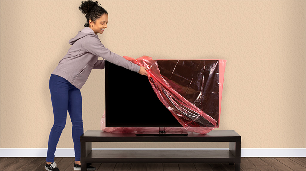 A woman begins to pack her TV before moving the TV to her U-Haul truck.