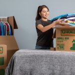 A woman starts packing her clothes into her moving boxes to help her move.