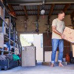 A man begins the processing of organizing his garage by moving boxes.