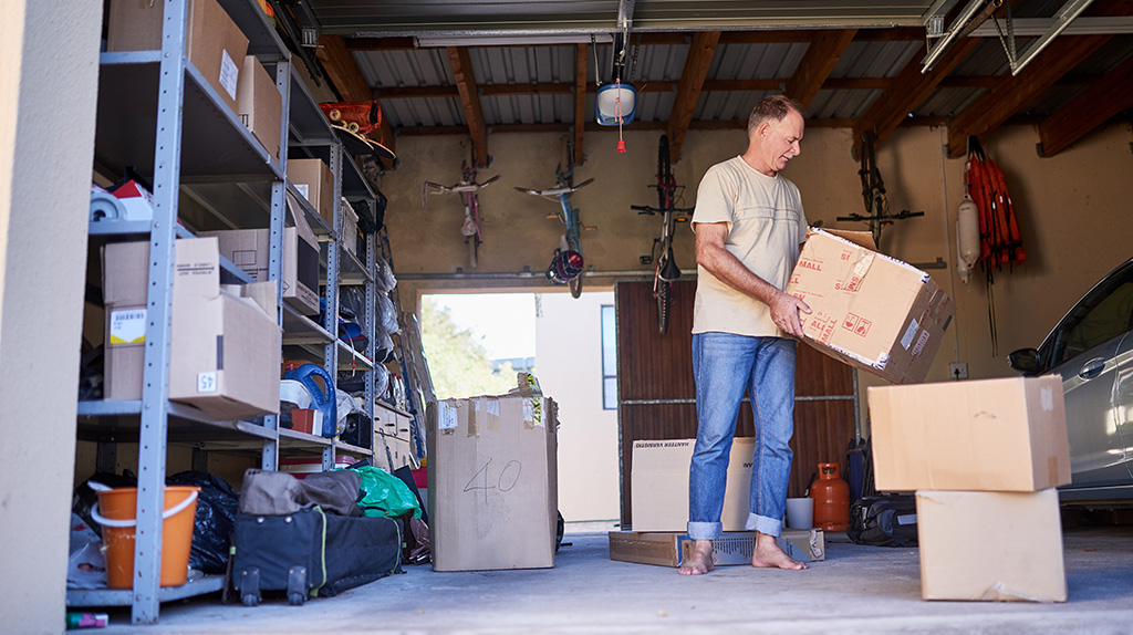 A man begins the processing of organizing his garage by moving boxes.