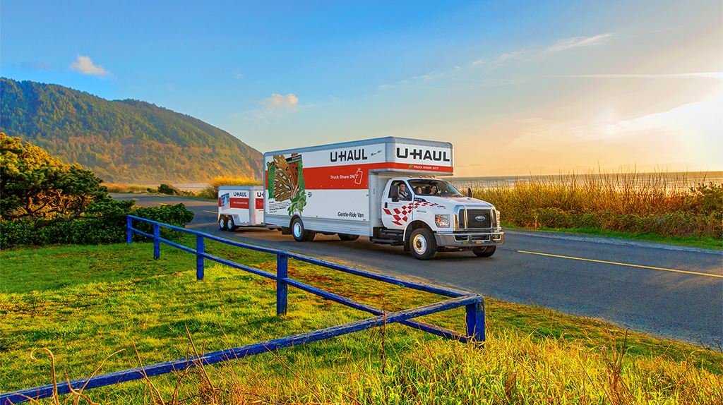 A U-Haul truck rental pulls a trailer driving to Oregon.