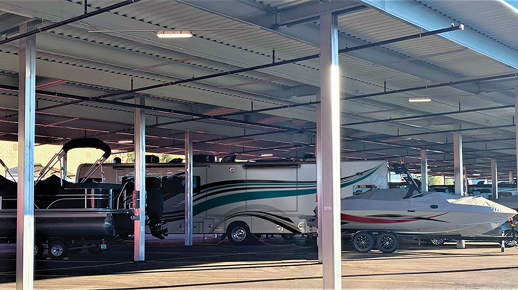 Boats and RVs are parked underneath an outdoor covered car storage area. In addition to car storage for cars, you also can store boats, RVs, pickup trucks, motorcycles, and other vehicles.