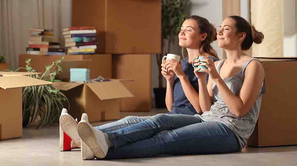 Two women relax in their first apartment after having all their belongings moved into it.