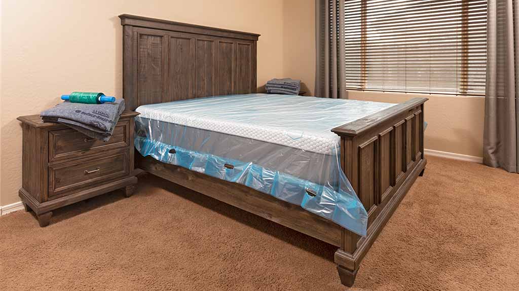A bedframe and a mattress sits in a bedroom. A mattress and bedframe are must-have items on your first apartment checklist.