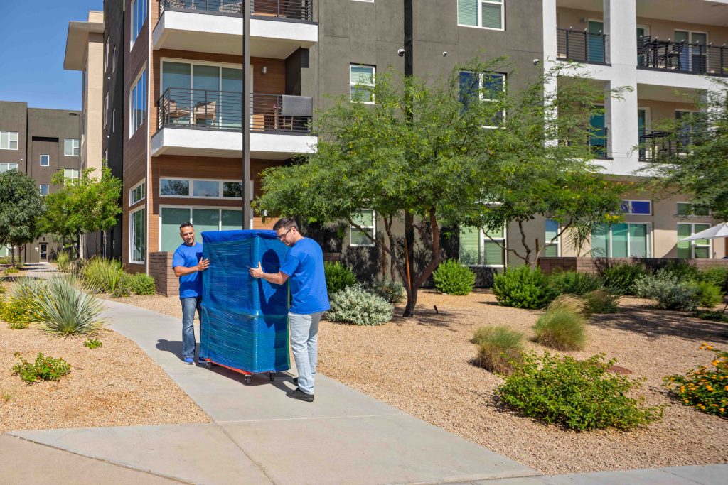 Two movers carefully move a furniture piece to a customer’s rental truck during their loading process.