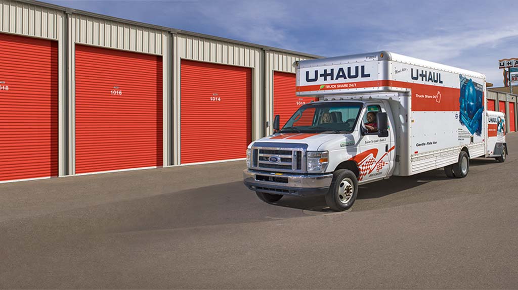 A couple stops driving their U-Haul truck rental after arriving at their storage unit. Professional movers can load or unload a storage unit when you’re moving, have a home renovation project, and more.