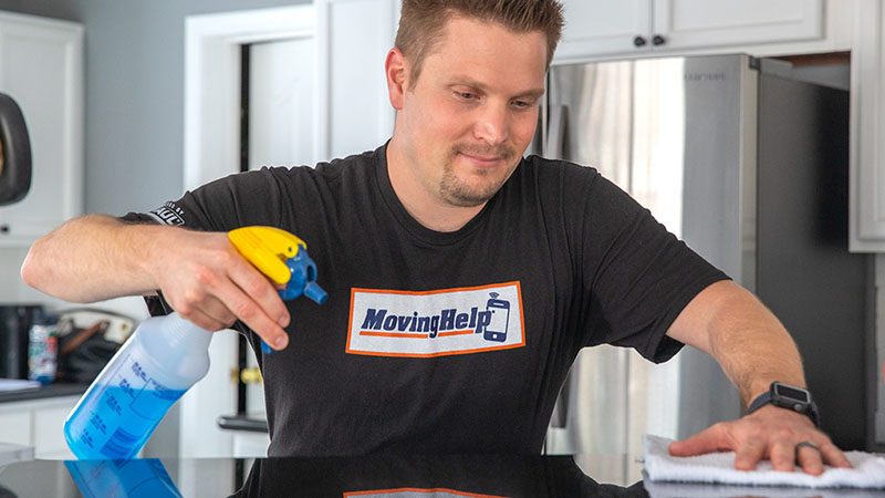 A mover wipes down the countertop to complete the apartment cleaning checklist.