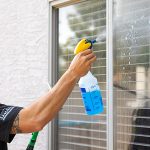 A Moving Helper sprays the window with a cleaning product. If you clean your apartment after moving out, you’re more likely to receive your entire cleaning deposit back.