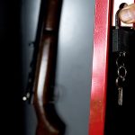 A person opens a gun safe with their keys.