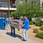 Four Moving Help Service Providers carry furniture out of a customer’s home and into their truck rental.
