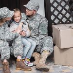 Military parents sit with their daughter on their porch with moving boxes.