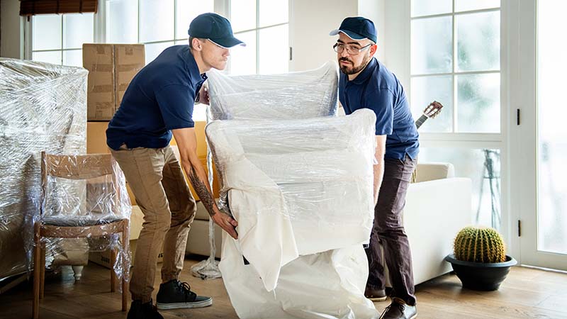 Two full-service movers begin to load a chair in preparation for a full-service move.
