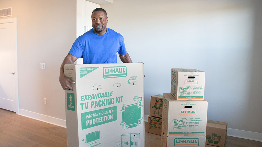 A moving labor provider carries a customer’s TV inside a TV packing kit.