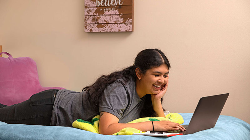 A college student enjoys hanging out in her dorm room.