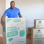 A Moving Help Service Provider carefully moves a U-Haul TV moving box for a customer.