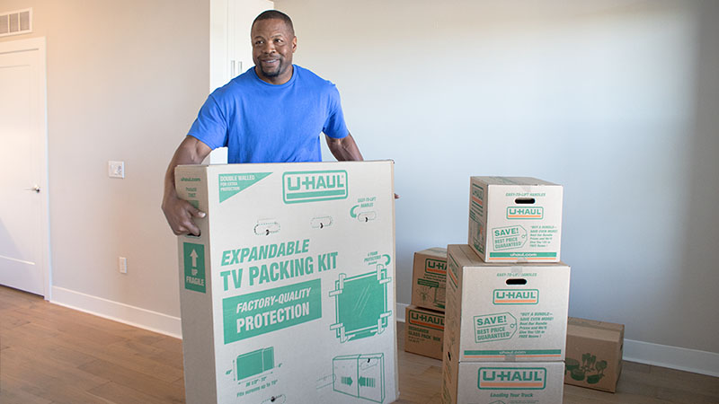 A Moving Help Service Provider carefully moves a U-Haul TV moving box for a customer.