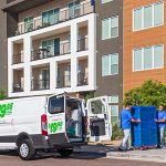 Two moving labor providers help load furniture into a U-Haul cargo van. A woman hired Moving Helpers to complete the load and unload portion of her hybrid move.