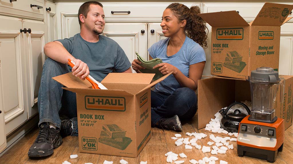 A couple starts to unpack their U-Haul book boxes. While the book box is excellent for carrying books, you also can place small, but heavy items into the book boxes for full protection.