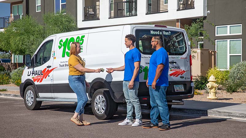 A woman hands cash to two male Service Providers from the Moving Help Marketplace who did a great job by completing a loading move from the customer’s apartment to her cargo van rental.