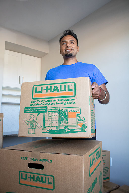A moving labor provider lifts a U-Haul small moving box in a customer’s home to bring to the U-Haul truck rental.