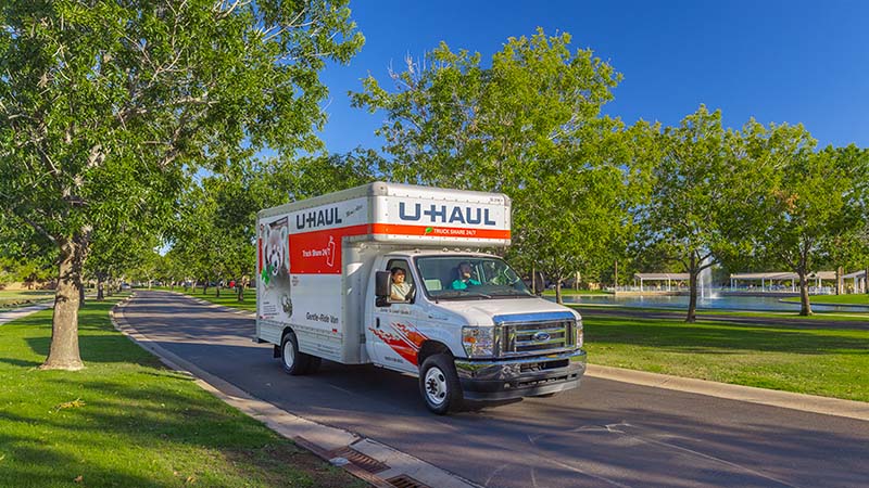 A customer drives a U-Haul truck rental in a scenic neighborhood.