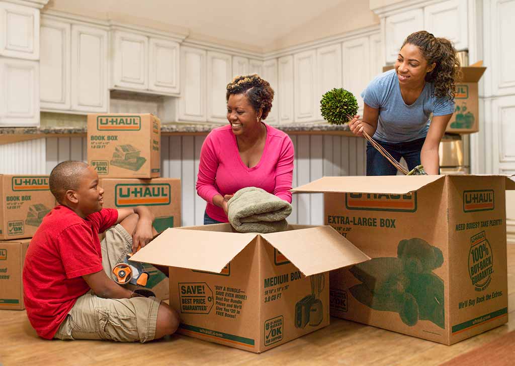 A mother packs her kitchen for moving with the help of her two children.