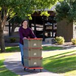 A woman pushes her Ready-To-Go U-Haul box outside from her apartment to her truck rental. When is the best time to rent an apartment will depend on your personal preferences.