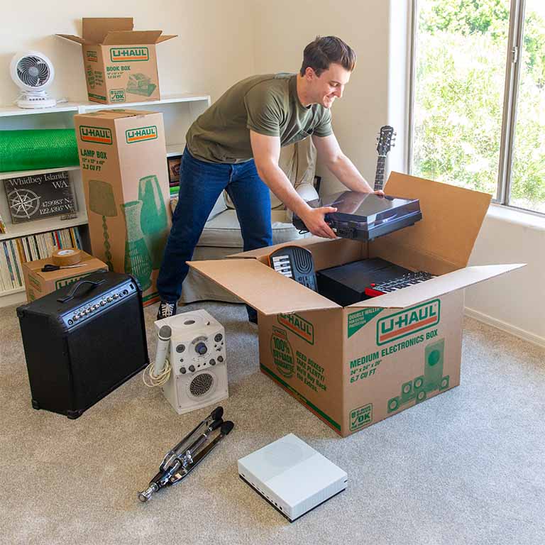 A customer starts packing his electronics and gaming consoles into a medium electronics moving box.