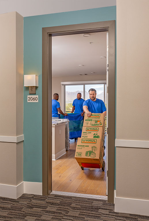 Three Service Providers are moving furniture and moving boxes out of an apartment.