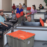 Business employees start packing office supplies as they prepare for their upcoming move using U-Haul Ready-To-Go box. Moving businesses doesn’t have to be difficult when you use Moving Help.