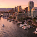 An aerial photo shows the sun beginning to set on a Canadian city next to a body of water.