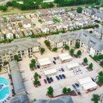An aerial photo shows townhouses lined next to one another along with amenities like a pool and grassy areas.