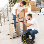 Two Moving Helpers work together to disassemble a shelving unit for a customer. The answer to the question, “Do movers disassemble furniture,” and the answer is yes, most moving labor teams disassemble furniture.