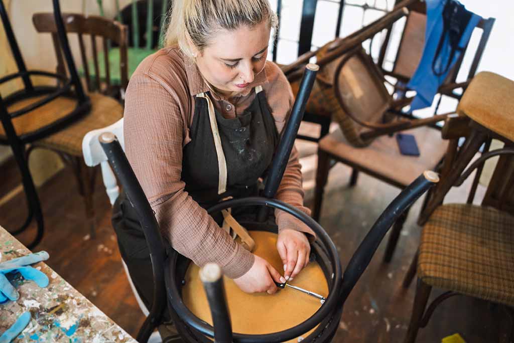 A woman works on disassembling her bar stool before her upcoming move.