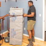 Two Moving Helpers from the Moving Help Marketplace work together to carefully prepare to move a gun safe on a utility dolly.