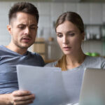 A man and a woman sit on the couch together as the couple tries to figure out their bad credit score.