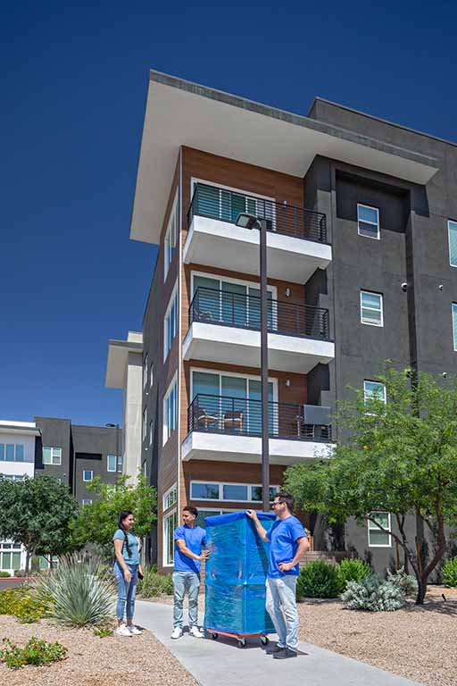 Two Service Providers talk to a female customer as they hold onto a piece of furniture that’s on a furniture dolly.