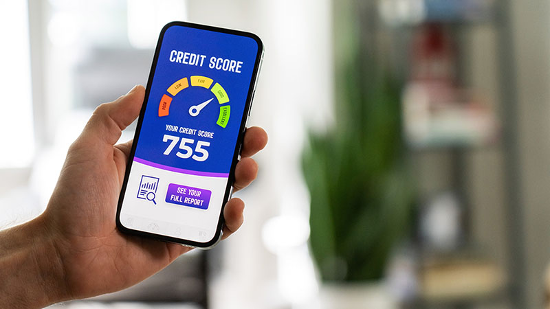 A man holds his iPhone showing his credit score. His credit score is 755, which is considered a “Good” score.