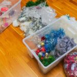 Holiday decorations lie in plastic storage bins and on the ground. You can use plastic bins to solve your “How to store holiday decorations” problem.