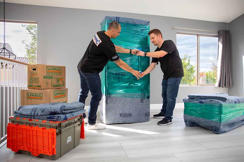 wo Moving Helpers use plastic stretch wrap to keep the furniture blanket on a piece of furniture in a customer’s home. You’ll want to understand your new job’s relocation policy before you begin moving.