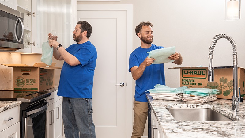 Two Moving Helpers are packing a customer's kitchen items in an apartment. 