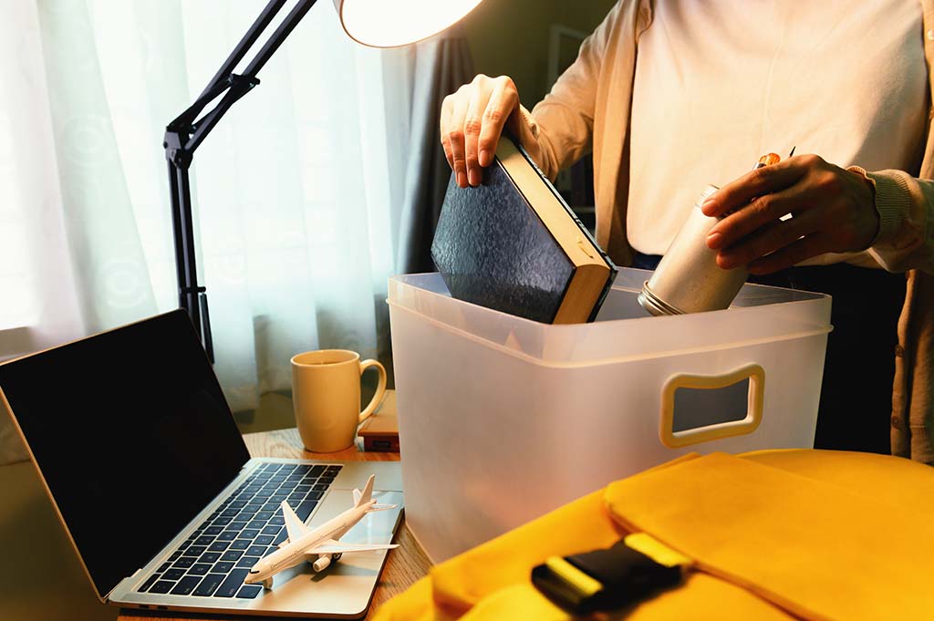 A woman packs some of her belongings at her desk as she prepares to move abroad.