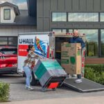 A husband and wife couple unload items out of their U-Haul cargo trailer and into their new home as a first-time homebuyer.