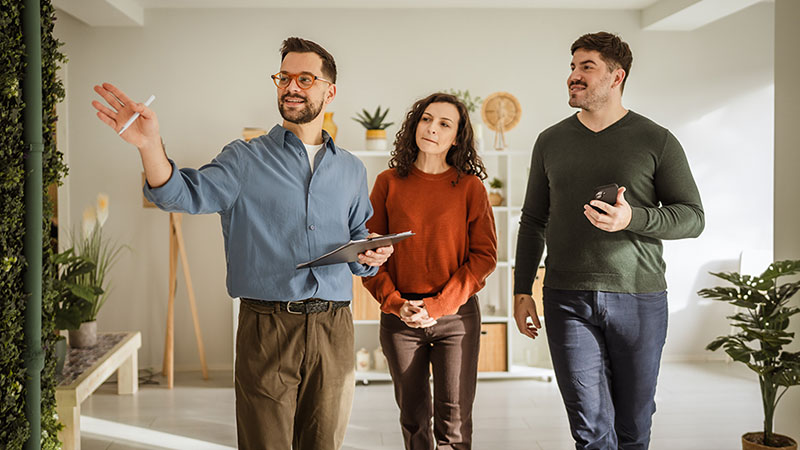 A male real estate agent shows a potential house for a husband-and-wife couple.