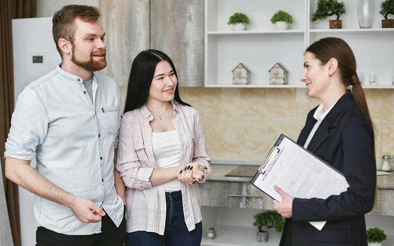 questions-to-ask-first-time-buyer-1 A young couple is meeting with their real estate agent to ask questions about buying a house.