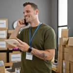 A man talks on the phone while looking around his office as he continues to pack before beginning his employer relocation assistance journey.