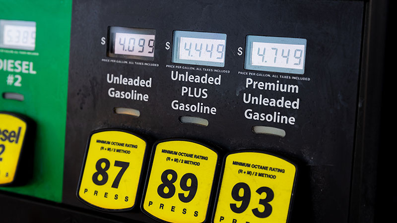 A gas station pump shows Unleaded Gasoline costing $4.099, Unleaded PLUS Gasoline costing $4.449, and Premium Unleaded Gasoline costing $4.749.